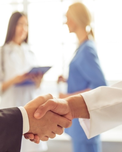 Two people shaking hands in dental office