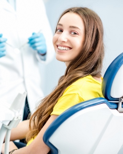 Woman in yellow blouse smiling in dental chair