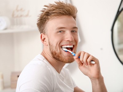 Closeup of man smiling while brushing his teeth