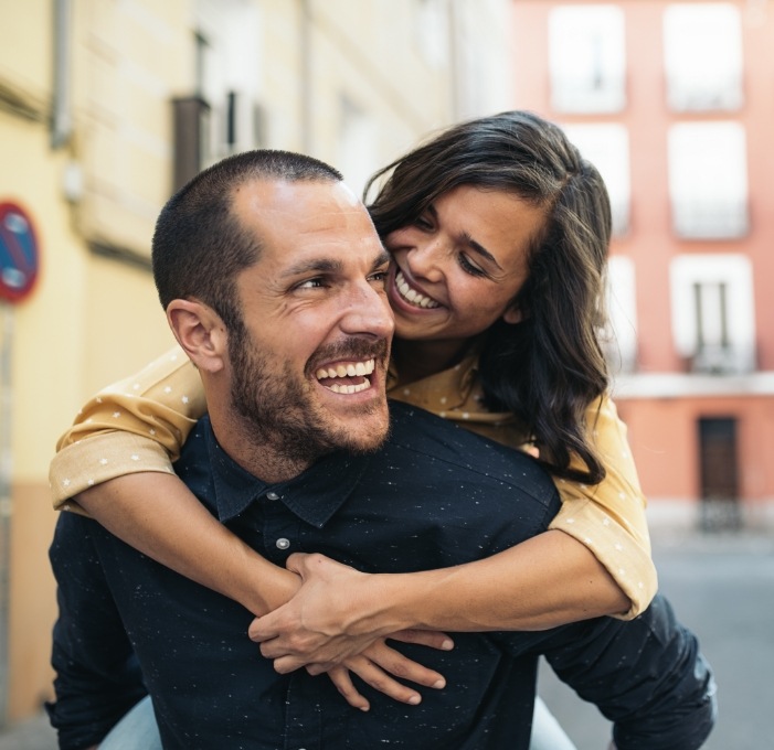 Man and woman hugging outdoors and smiling after cosmetic dentistry in Mississauga