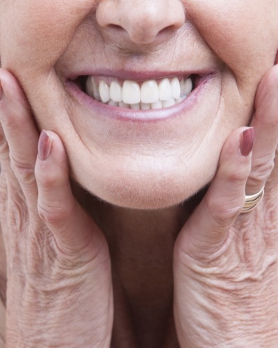 Close up of smiling senior woman touching her face