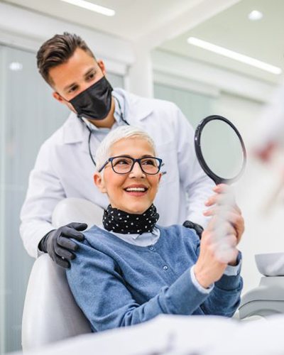 Mature female dental patient looking in mirror