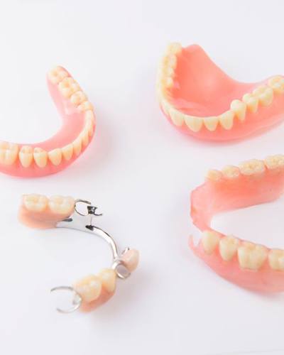 Full and partial dentures arranged against neutral background