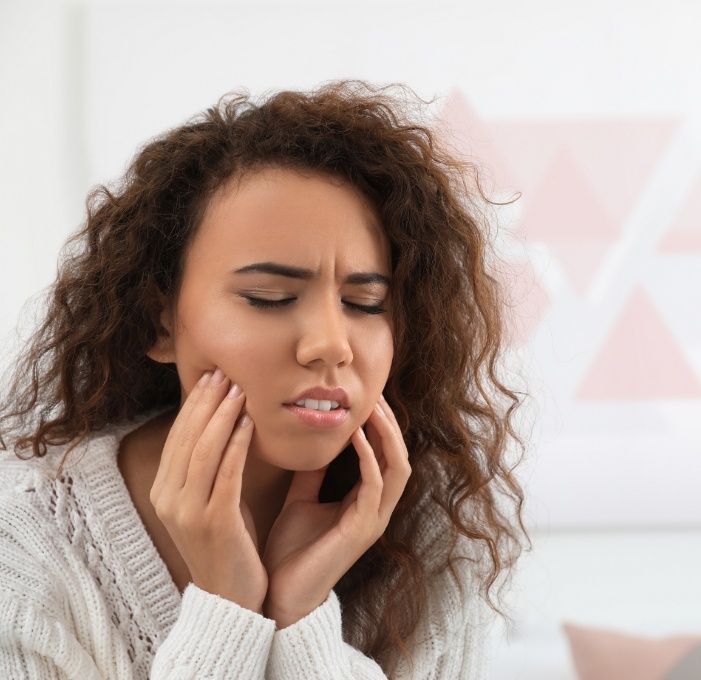 Woman holding her face in pain needing emergency dentist in Mississauga