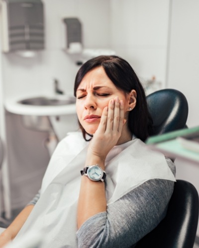 Dental patient holding her cheek in pain