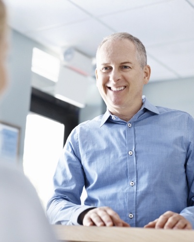 Man smiling at dental office receptionist