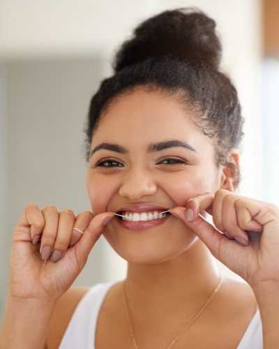 Woman smiling while flossing her teeth