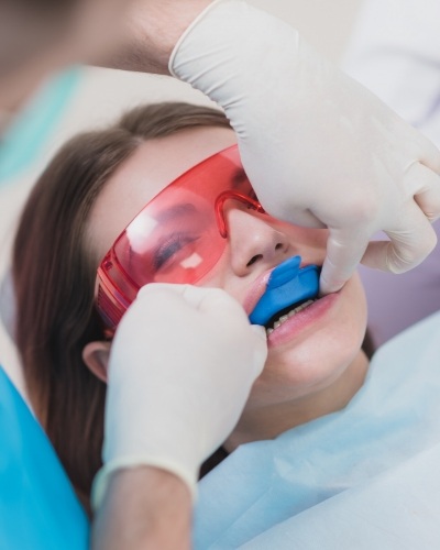 Young woman in dental chair with fluoride trays on her teeth