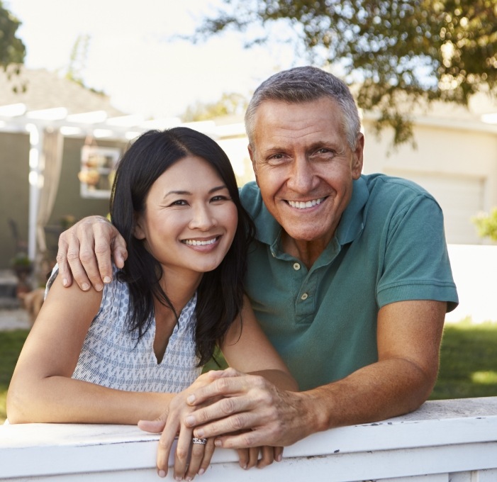 Man and woman smiling together in their front yard