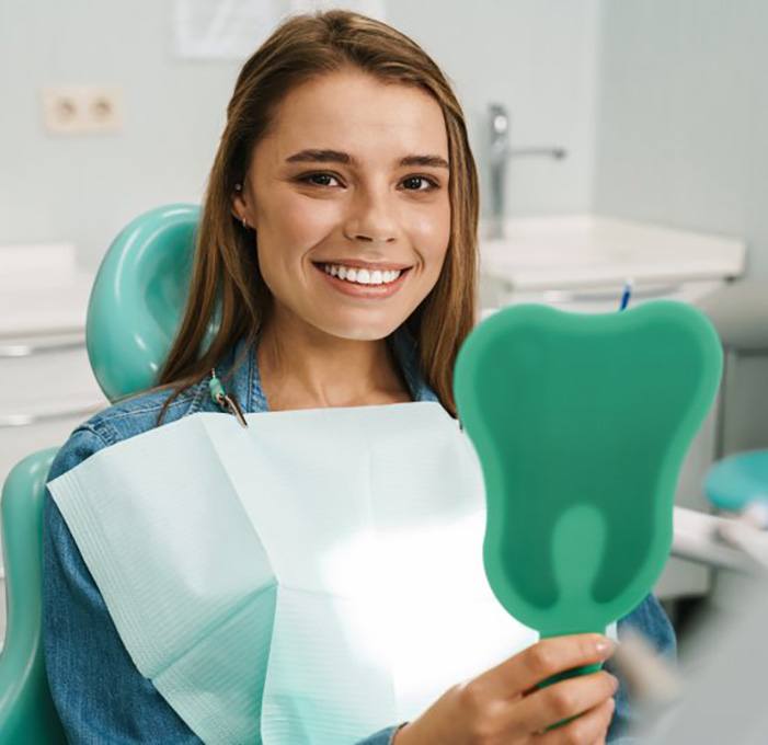 a patient checking her smile with a mirror