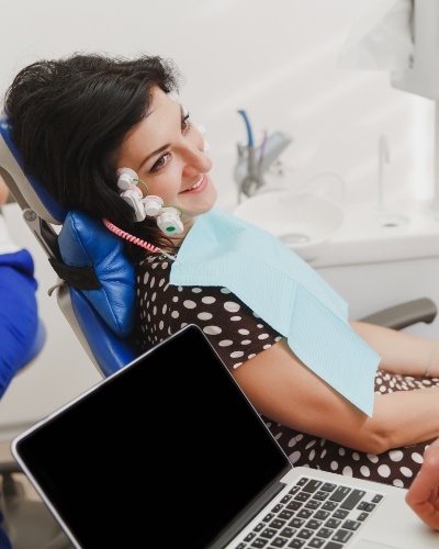 Smiling woman in dental chair receiving T M J treatment