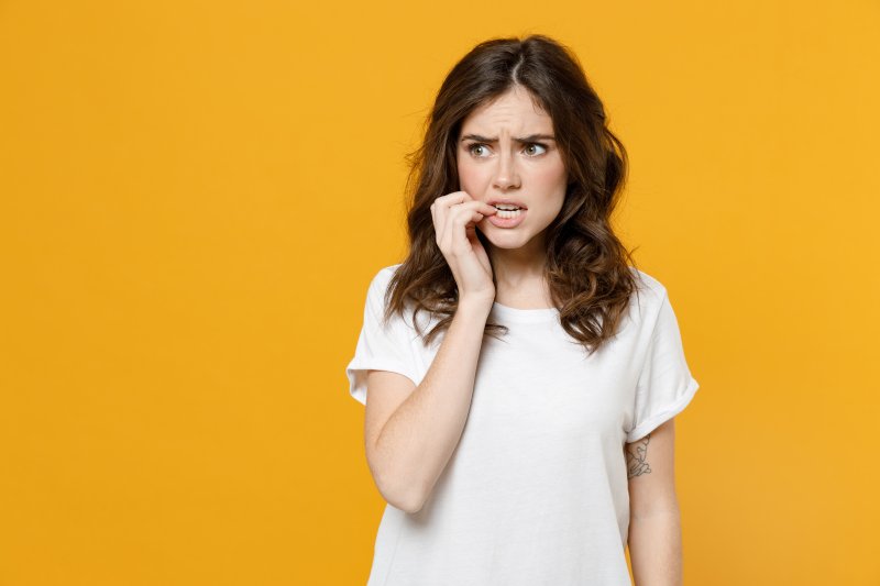 Woman with a dental implant biting her nails