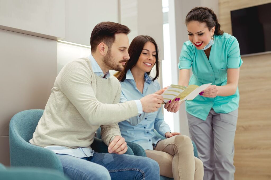 A dentist reviewing dental insurance coverage with a man and woman.