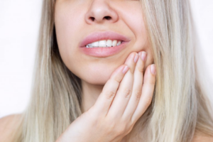 Close up of woman rubbing her sensitive tooth