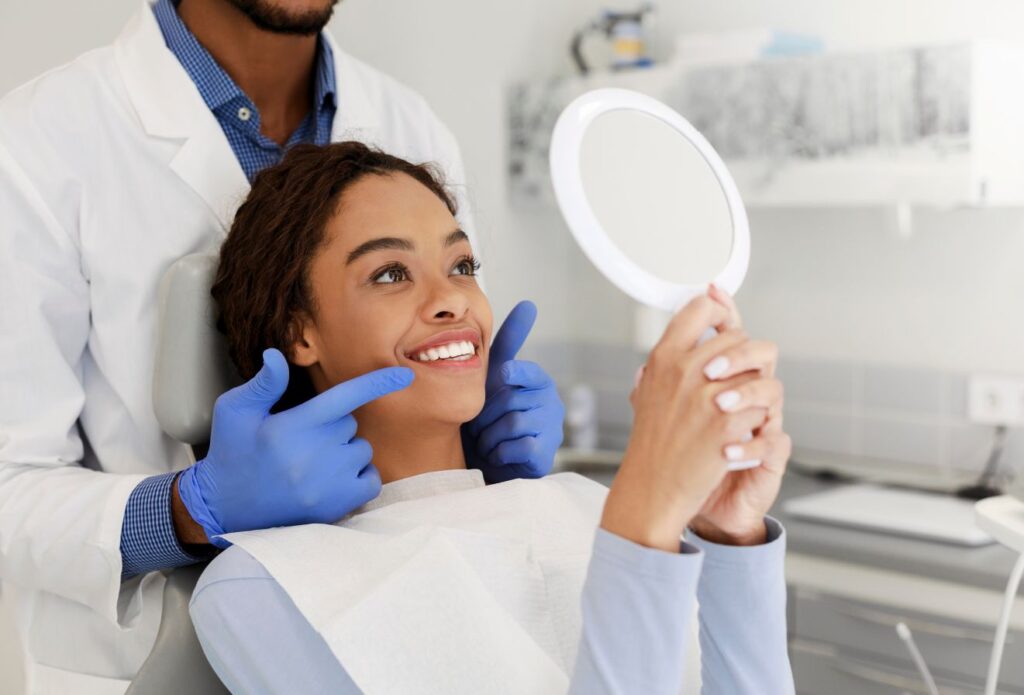 A woman smiling in the mirror at the dentist.